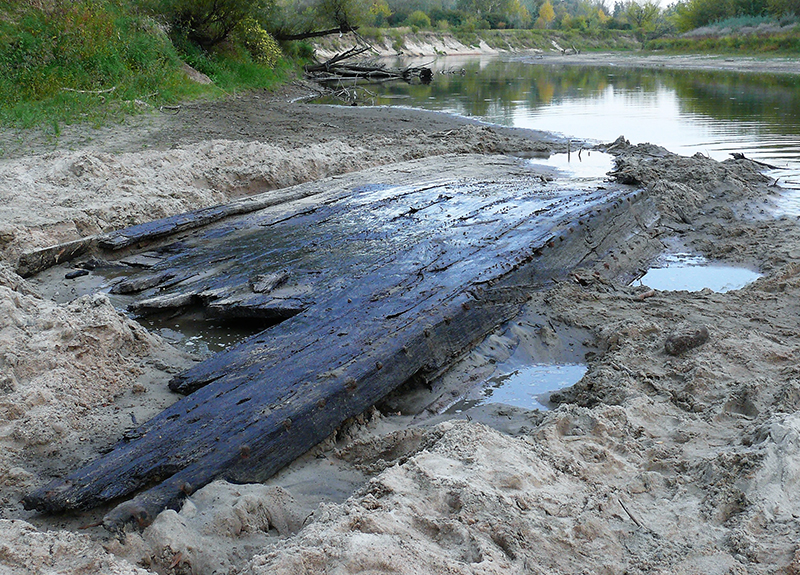 brzeg rzeki z zakopaną starą łodzią
