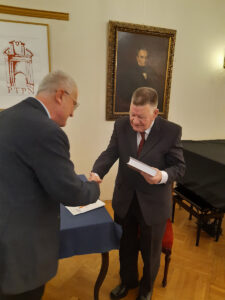 Uścisk dłoni dwóch osób; jedna z nich trzyma książkę